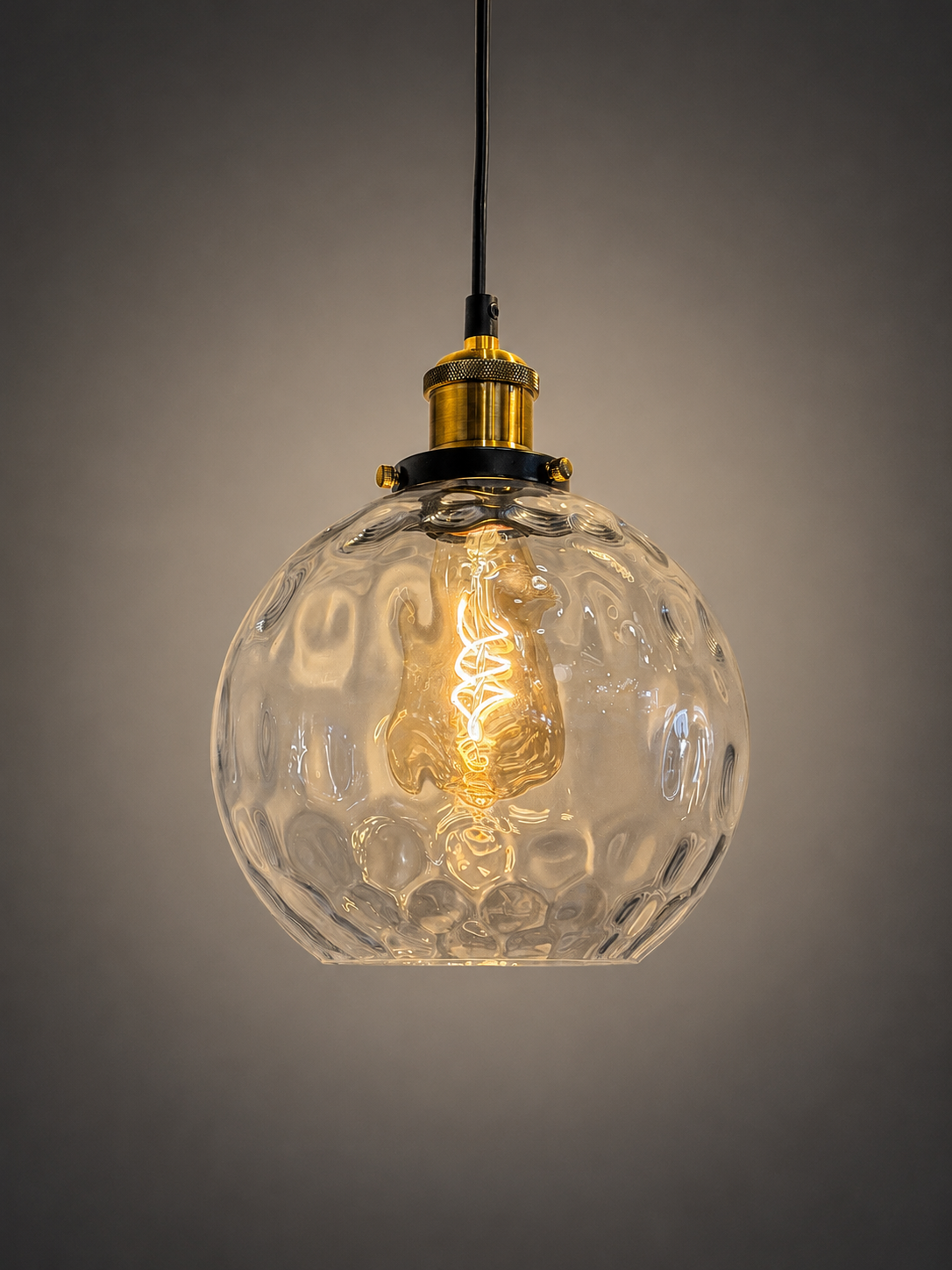 A hanging pendant light with a clear textured glass globe shade