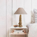 Decorative lamp on a nightstand next to a bed with white bedding nz