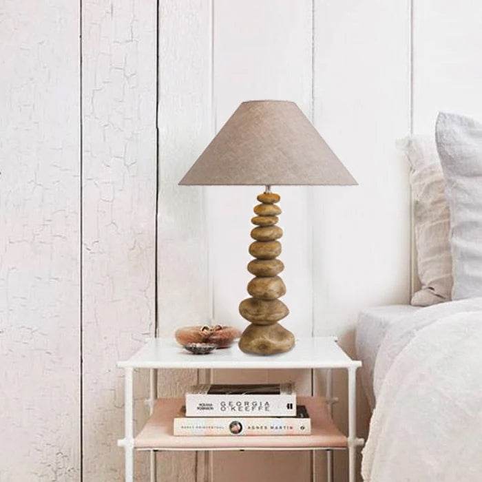 Decorative lamp on a nightstand next to a bed with white bedding nz