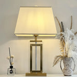 Decorative table lamp with a gold base and white shade on a surface west auckland