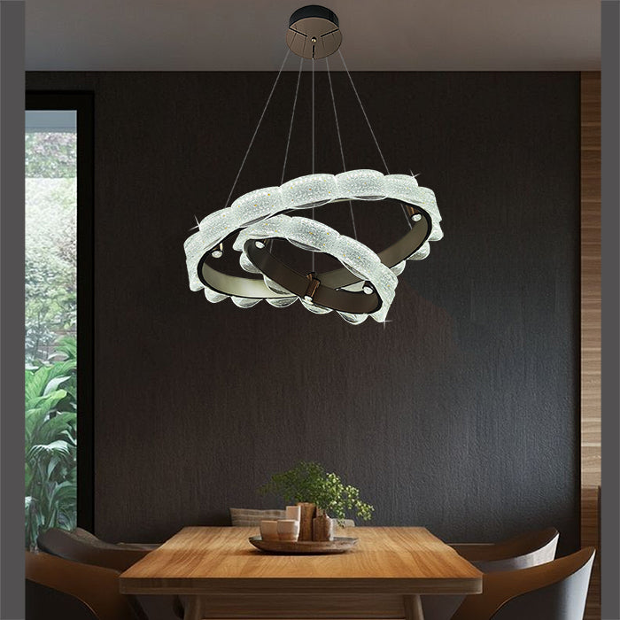 Modern chandelier hanging above a dining table with a dark wall nz