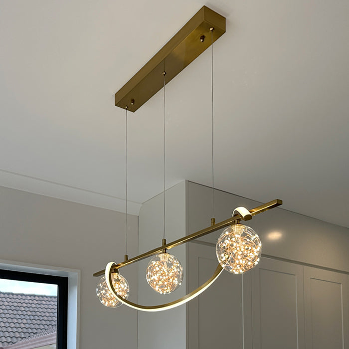 Modern island light fixture with gold finish and crystal-like glass shades in a room setting nz