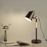 Modern table lamp on a desk with a magazine and vase in a warm setting nz