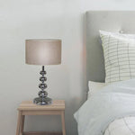 Table lamp on a nightstand next to a bed nz