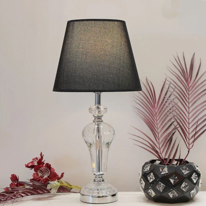 Table lamp with black shade and clear glass base on a white surface nz