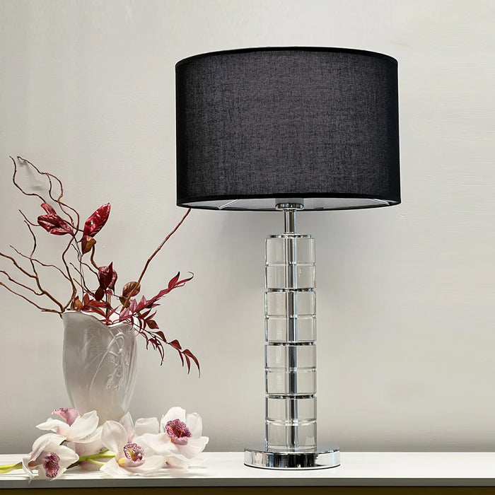 Table lamp with a black shade and clear cylindrical base on a surface west auckland