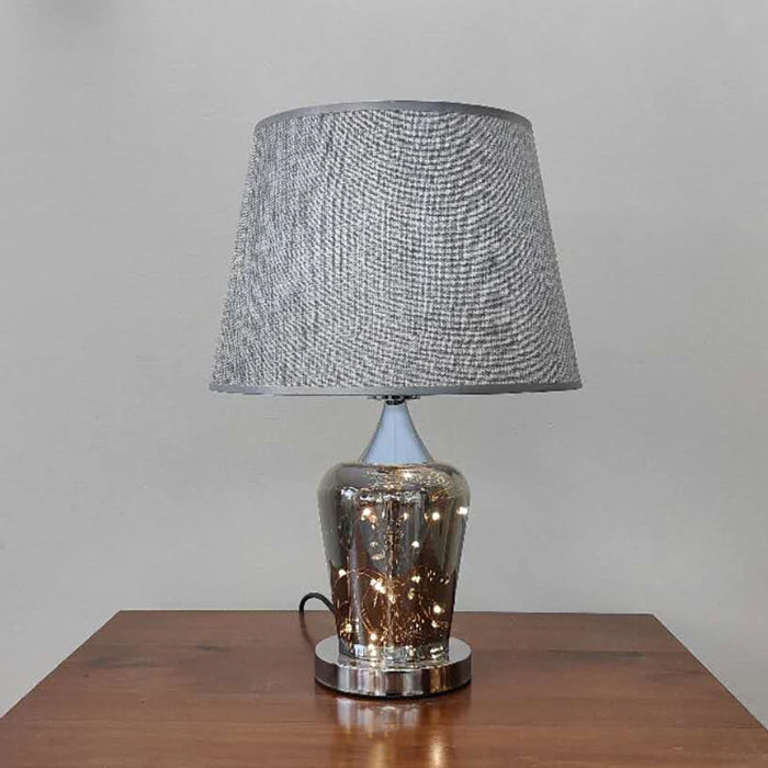 Table lamp with textured gray shade and metallic base on a wooden surface nz