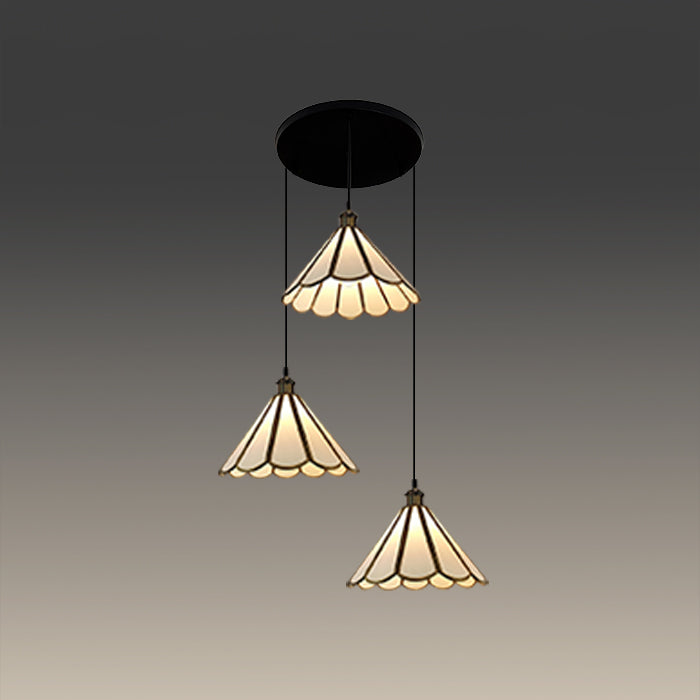 Three-tiered pendant light with stained glass design above tablenz
