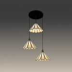 Three-tiered pendant light with stained glass design above tablenz