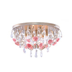 A brass-colored ceiling light fixture with clear crystals and pink ceramic flowers NZ